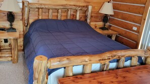 A wooden cabin room with a bed, two nightstands, and a table. - Large garage for bikes. Beautiful log home.  On golf course. (Hulett)