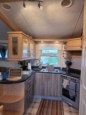Una cocina compacta para autocaravana con estufa integrada, fregadero y una pequeña zona de comedor.