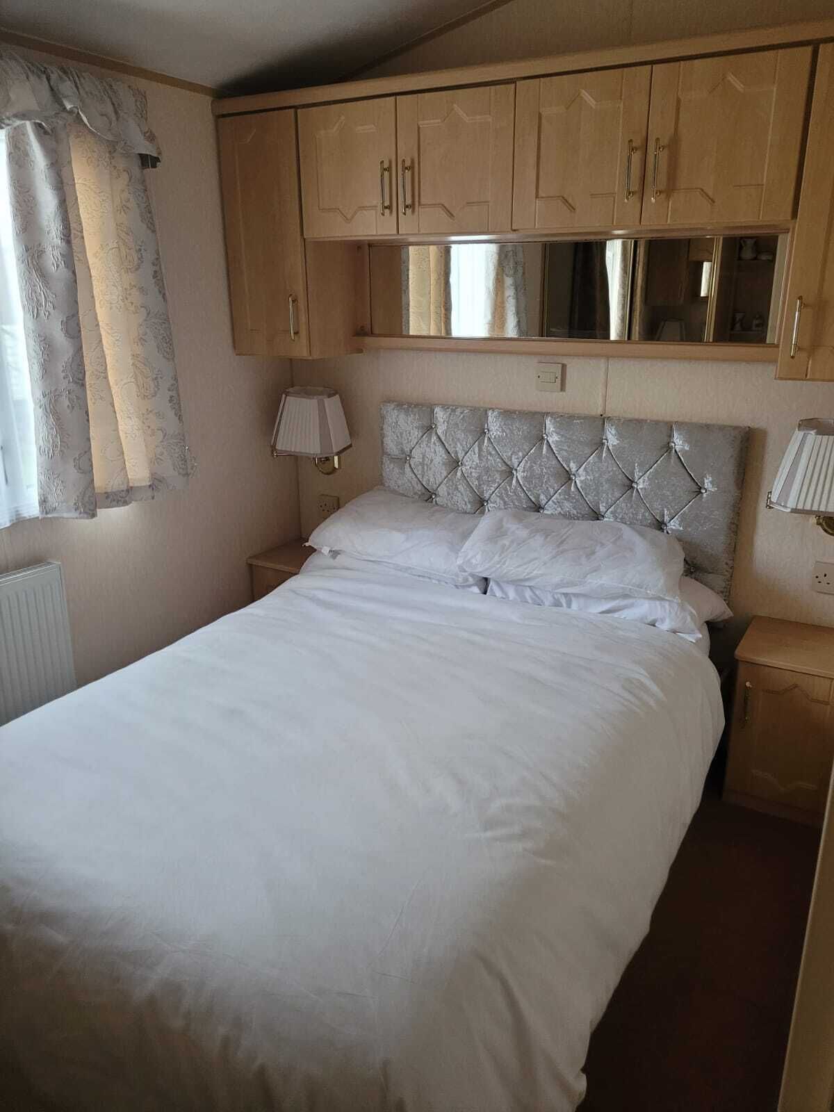 A bedroom with a bed, a nightstand, a lamp, and wooden cabinets.