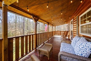 Eine Holzterrasse mit Korbmöbeln und Blick auf einen Wald.