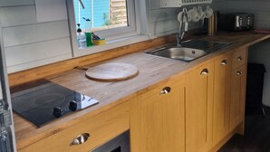 Una cocina compacta con armarios de madera, un lavamanos de acero inoxidable y un horno empotrado.