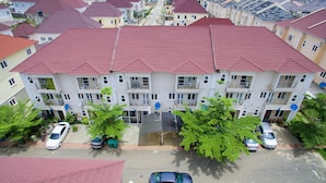 A multi-story residential building with a red-tiled roof, multiple balconies, and satellite dishes. - Charming 1-Bed Apartment in Abuja (Abuja)