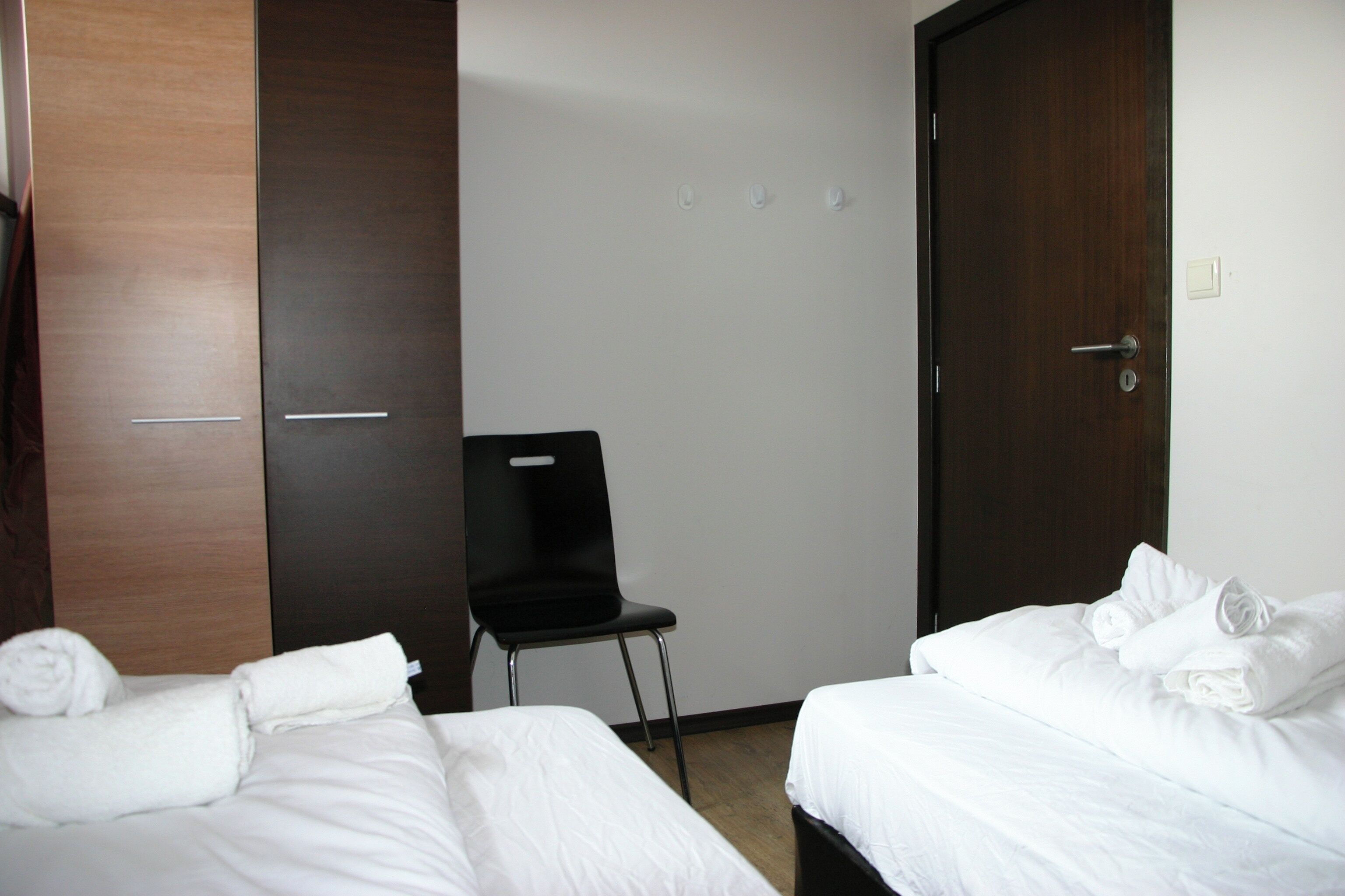 Una habitación de hotel con dos camas, una silla, un armario y una puerta.