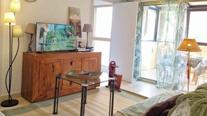 Een woonkamer met een houten kast, een televisie en een groot raam met gordijnen.