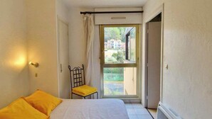 Een slaapkamer met een bed, een stoel en een raam.