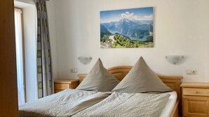 Ein Schlafzimmer mit einem hölzernen Bett, einem Nachttisch, einer Wandlampe und einem Gemälde einer Berglandschaft.