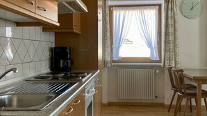 Eine Küche mit Holzausstattung, einem Herd und einem Fenster mit Vorhängen.