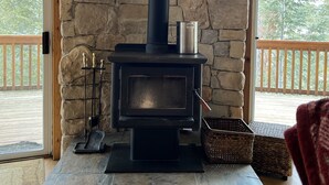 Una chimenea de piedra con un conducto negro, una olla de metal encima y una figura decorativa de un lobo.