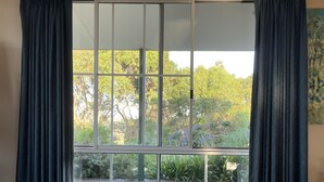Un dormitorio con una cama grande, una ventana con cortinas y vistas a zonas verdes.