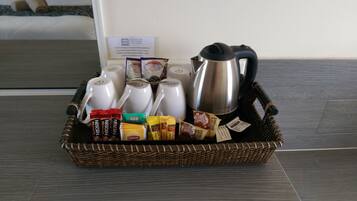 A wicker basket containing a Nescafe Blend 3 mug, a Nescafe Blend 4 mug, a Lipton tea sachet, a pack of biscuits, and a silver Maxim coffee pot.