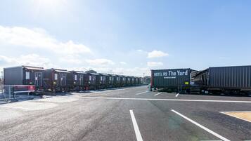 Een treinstation met meerdere treinwagons en een vrachtwagen met daarop 'HOTEL R9 The Yard'.