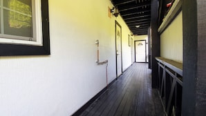 Un pasillo estrecho con suelo de madera, paredes blancas y detalles en negro.