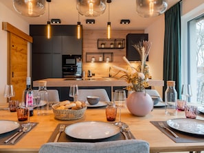 Enjoy meals in this stylish dining area with a wooden table set for a meal, featuring plates, cutlery, and glasses.