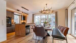 Una cocina moderna con una isla central, suelo de madera y un comedor con banco y sillas.