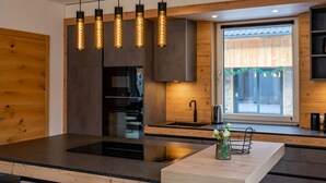 Una cocina moderna con una isla central, iluminación colgante y muebles de madera.