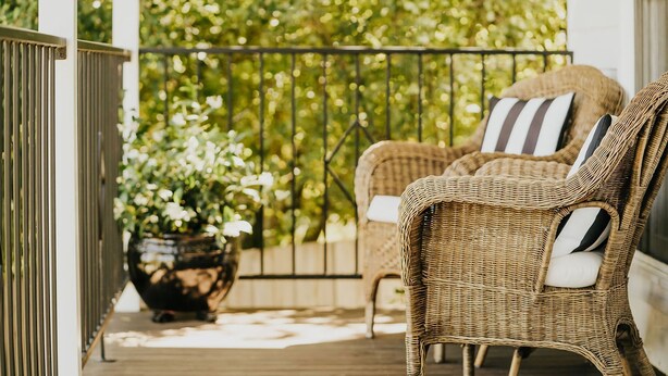 A wicker chair with a striped pillow on a wooden deck. - Candlebark Daylesford ~ Gorgeous Cottage! (Daylesford)