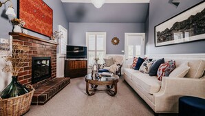 A living room with a fireplace, a television, a sofa, and a coffee table. - Candlebark Daylesford ~ Gorgeous Cottage! (Daylesford)