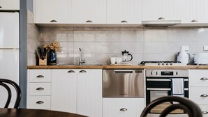 A modern kitchen with white cabinets, a stainless steel dishwasher, and a coffee maker. - Candlebark Daylesford ~ Gorgeous Cottage! (Daylesford)