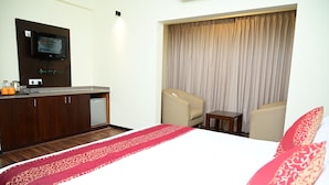 Una habitación de hotel con cama, escritorio, silla y televisión montada en la pared.