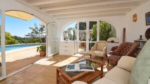 A spacious living room with a view of a swimming pool, comfortable seating, and a glass coffee table. - Ladera - Jesus Pobre, Costa Blanca (Jesus Pobre)
