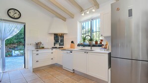 A modern kitchen with white cabinetry, a stainless steel refrigerator, a dishwasher, and a window with a view of greenery. - Ladera - Jesus Pobre, Costa Blanca (Jesus Pobre)