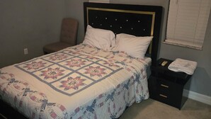 Un dormitorio con cama, una silla, una mesita de noche y un aparador.