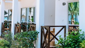 Un edificio moderno con varios balcones, mobiliario exterior y abundante vegetación.