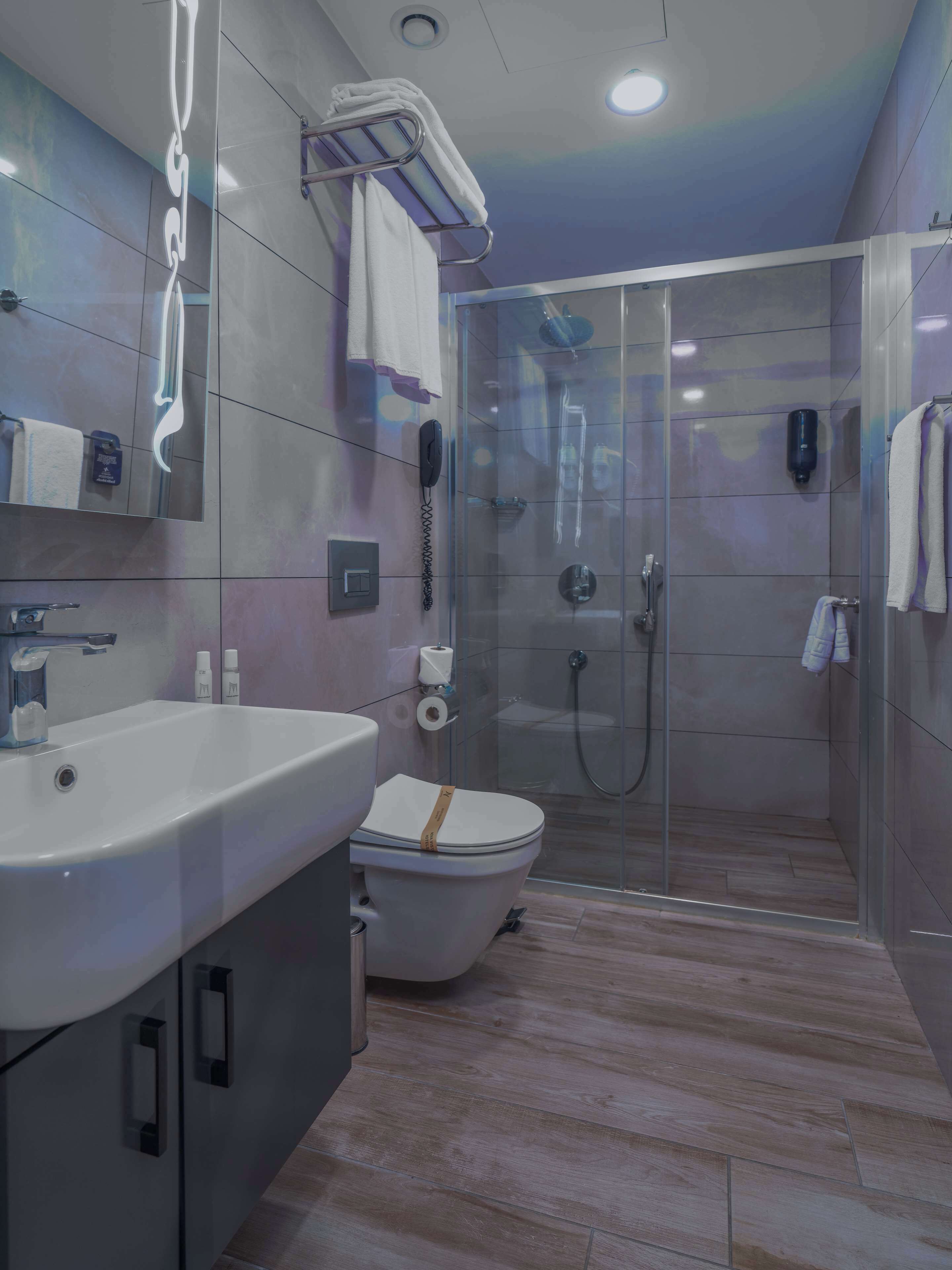 Un baño moderno con cabina de ducha de vidrio, un lavamanos blanco y un inodoro.