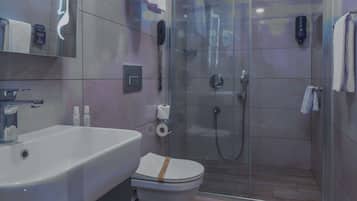 Un baño moderno con cabina de ducha de vidrio, un lavamanos blanco y un inodoro.