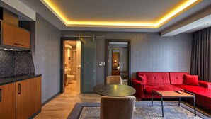 Un salon moderne avec un canapé rouge, une table ronde et un coin cuisine doté de meubles en bois.