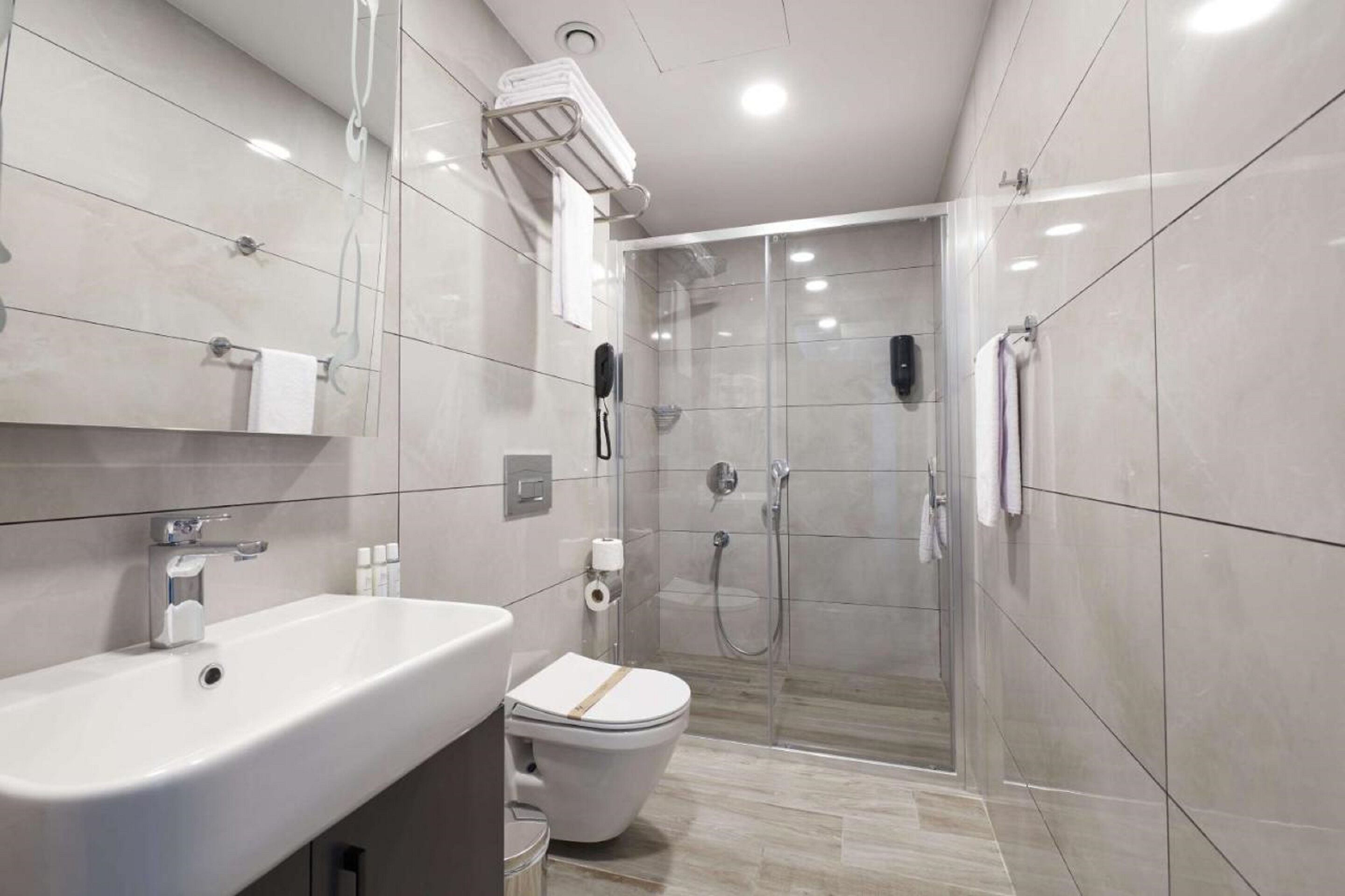 A modern bathroom with a sink, toilet, and glass-enclosed shower area.