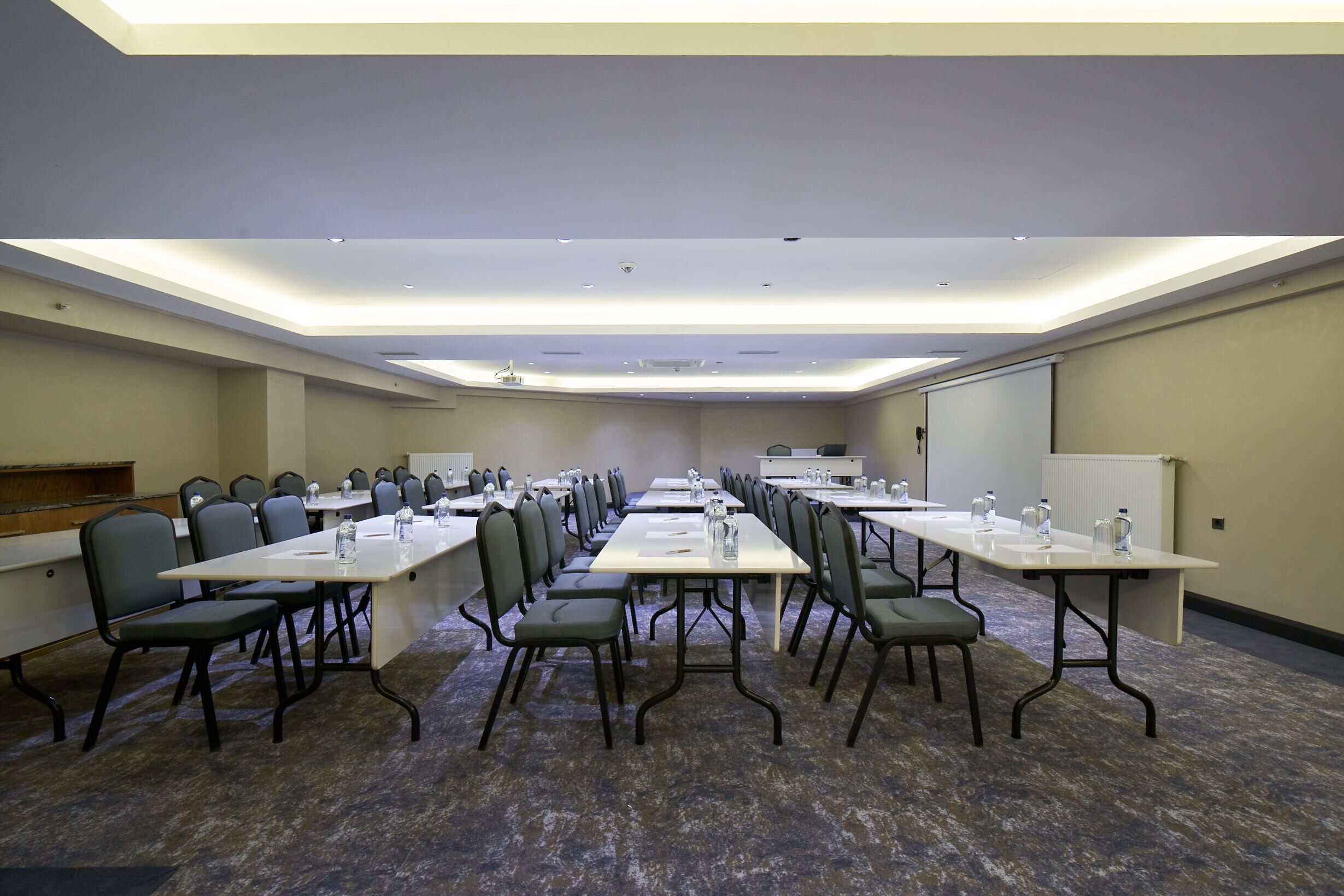 A conference room with multiple tables and chairs, equipped with water bottles and nameplates.