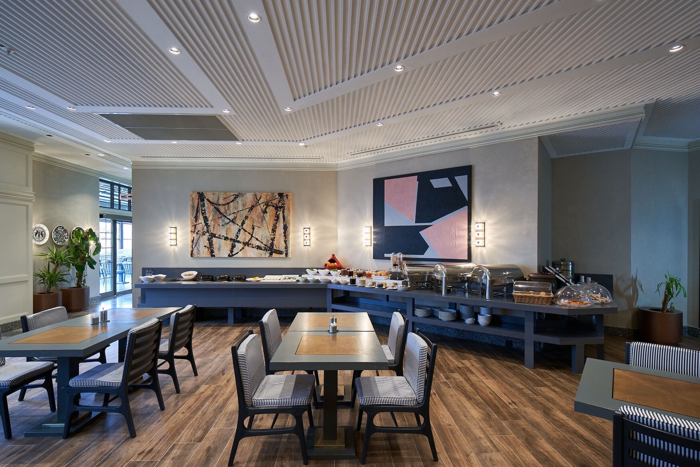A modern dining area with a long communal table, individual seating, and a buffet station.