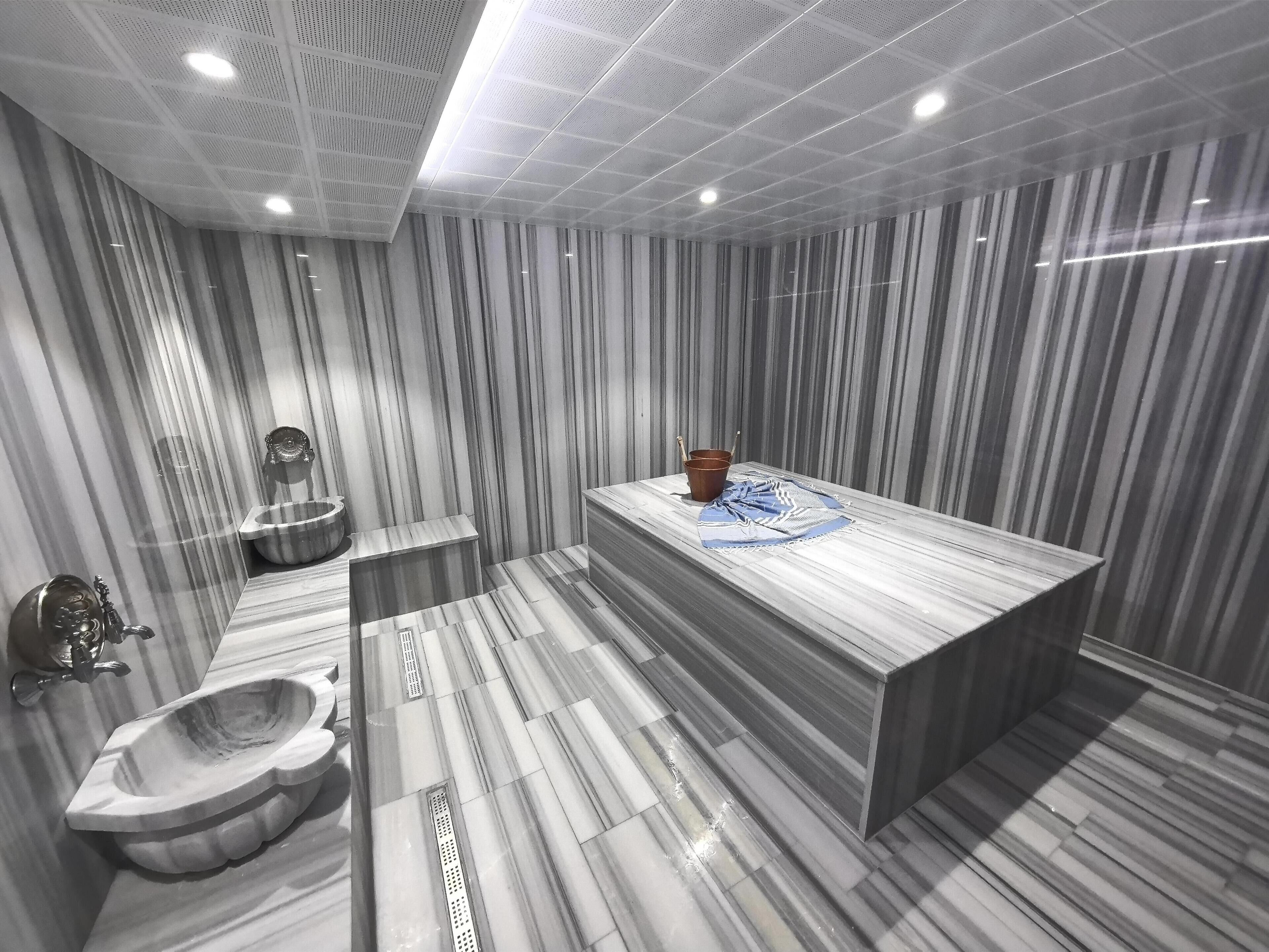 A modern bathroom with a marble vanity, a freestanding bathtub, and a large mirror.