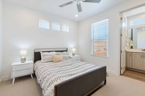 A bedroom with a bed, bedside tables, a ceiling fan, and a window with blinds.