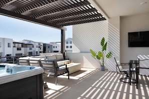 Relax in style with a hot tub and comfortable seating under a shaded pergola.