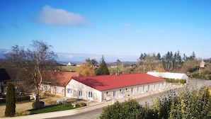 A large, single-story building with a red roof, surrounded by trees and a clear sky. - Independent residence sleeps 32 (Croisilles)
