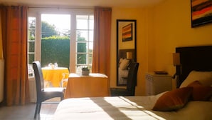 A hotel room with a bed, a desk with a chair, a table with a yellow tablecloth, and a window with curtains. - Independent residence sleeps 32 (Croisilles)