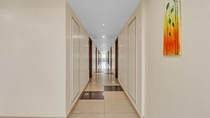 Un long couloir étroit, doté d’un sol à carreaux, de murs blancs et de portes de part et d’autre.