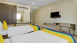 Une chambre d’hôtel avec deux lits, un téléviseur fixé au mur, un bureau et une chaise.