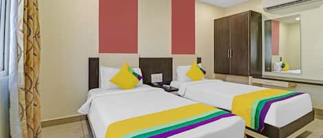 A hotel room with two beds, a large mirror, a wardrobe, and a ceiling fan.