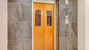 Un ascenseur moderne avec un mur en marbre et un plancher en bois.