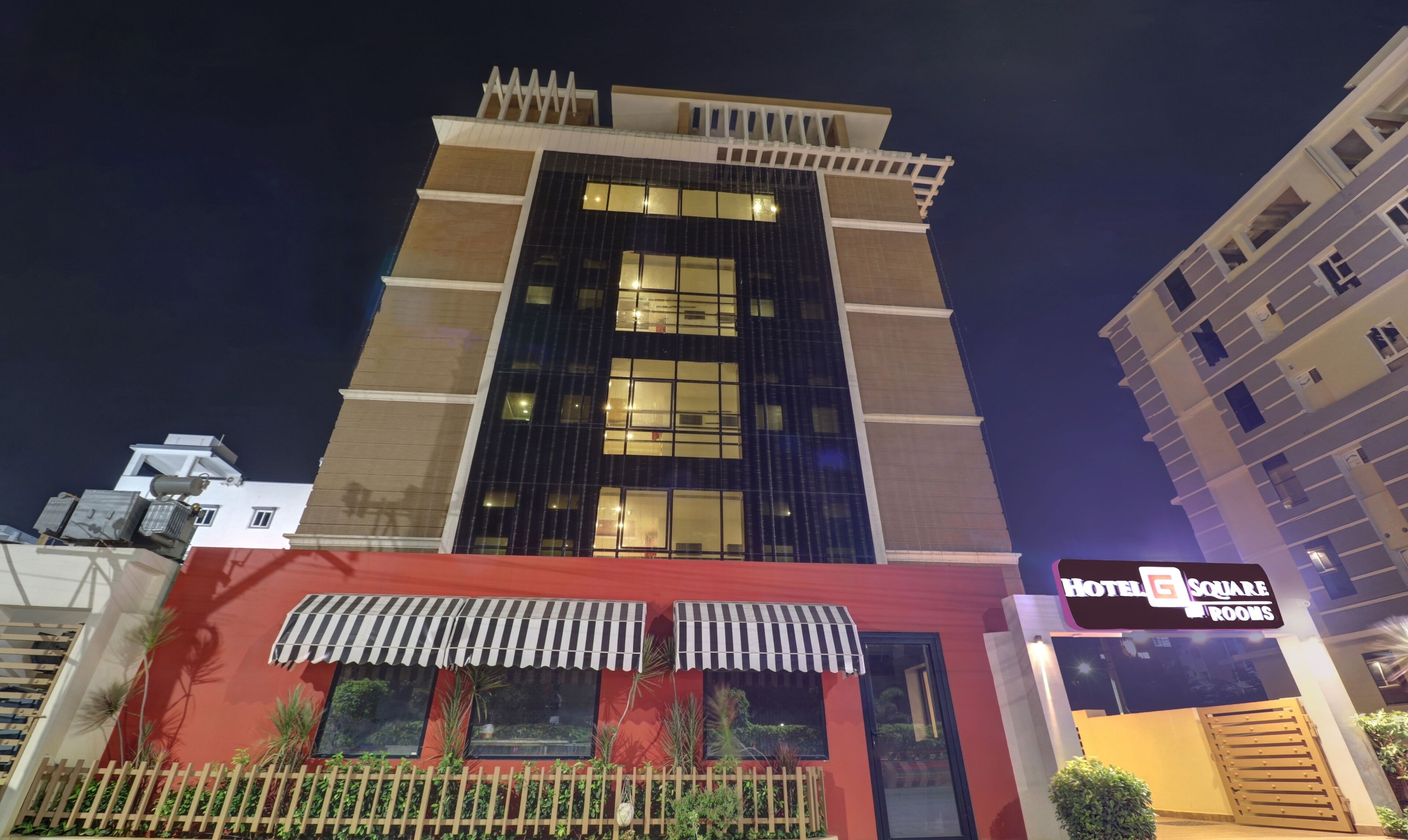 A hotel with a modern facade, large windows, and a sign indicating 'Hotel Square Rooms'.