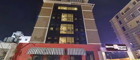 A hotel with a modern facade, large windows, and a sign indicating 'Hotel Square Rooms'.