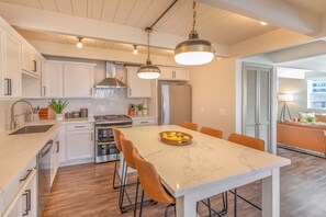 Una cocina moderna con armarios blancos, una isla de mármol y sillas color naranja.
