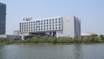 A modern building with a flat roof and a large glass facade, situated by a body of water.