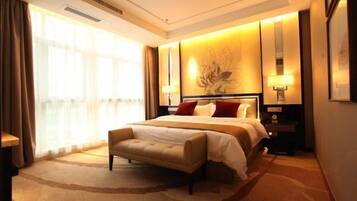 A hotel room with a large bed, a bench, a nightstand, and a wall-mounted lamp.