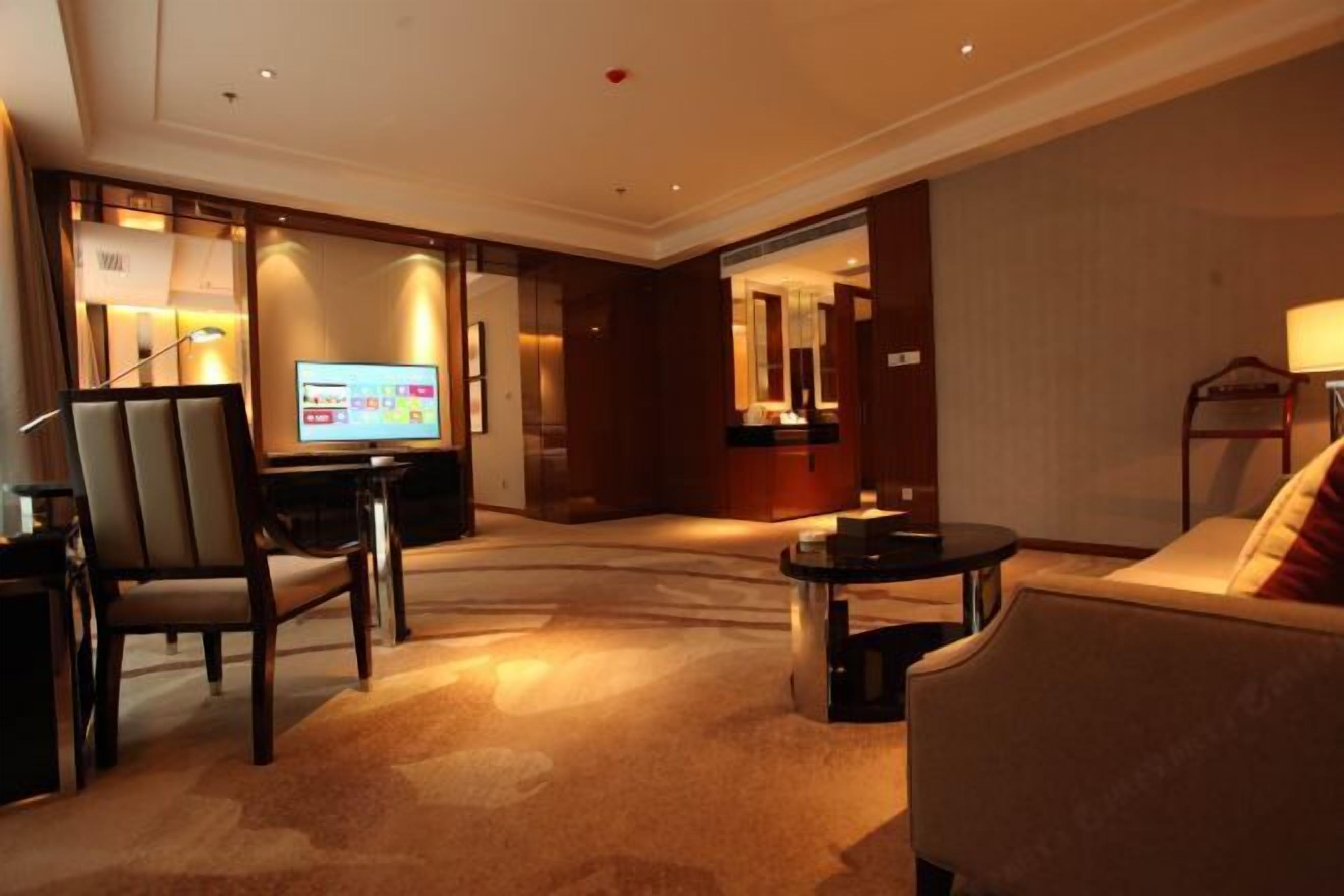 A hotel lobby with a television, seating area, and a reception desk.