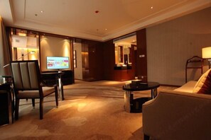 En hotellobby med en tv, en sittgrupp och en receptionsdisk.