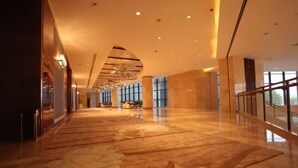 A spacious lobby with a polished marble floor, large windows, and a modern ceiling design.